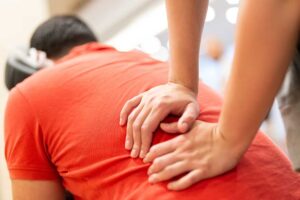Person gently stretching neck while sitting on a sofa in a bright, tidy living room.