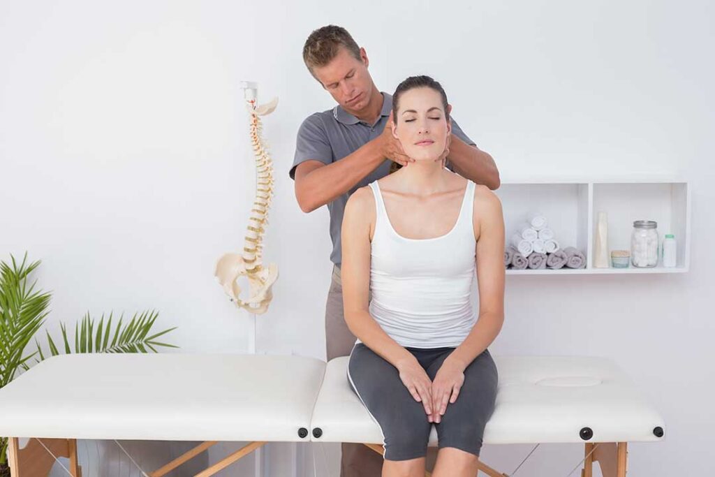 Person gently stretching a knee beside a chair with an ice pack and folded towel nearby.
